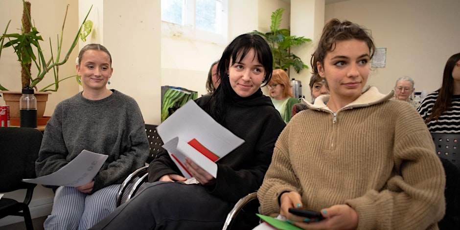 women hustings Three women sit in a waiting area holding papers and folders.